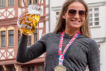 Coach Corky, wearing her Frankfurt Germany Marathon medal, toasts with a big stein of German beer